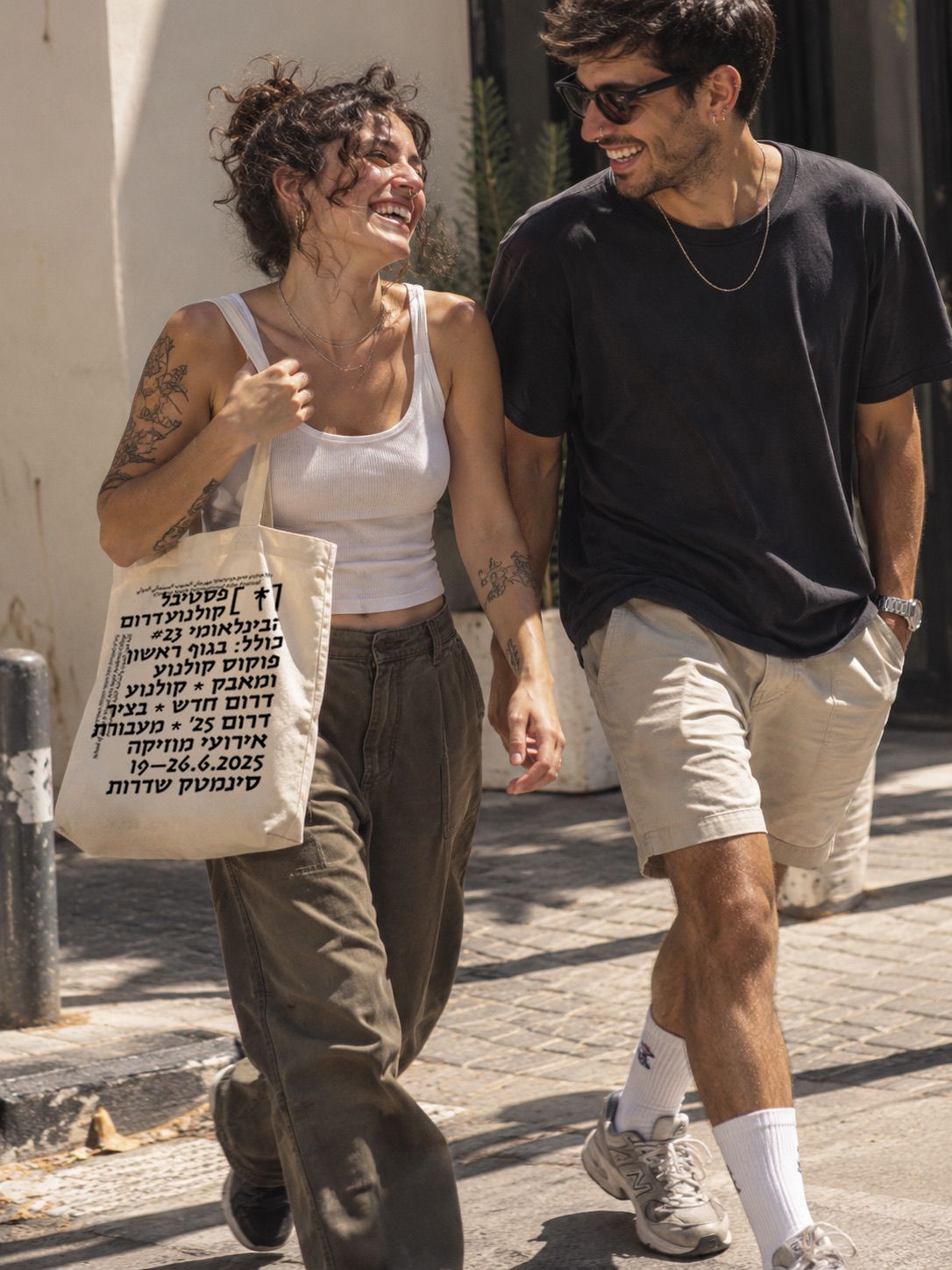 Two people walking in the street, one carrying the festival tote bag