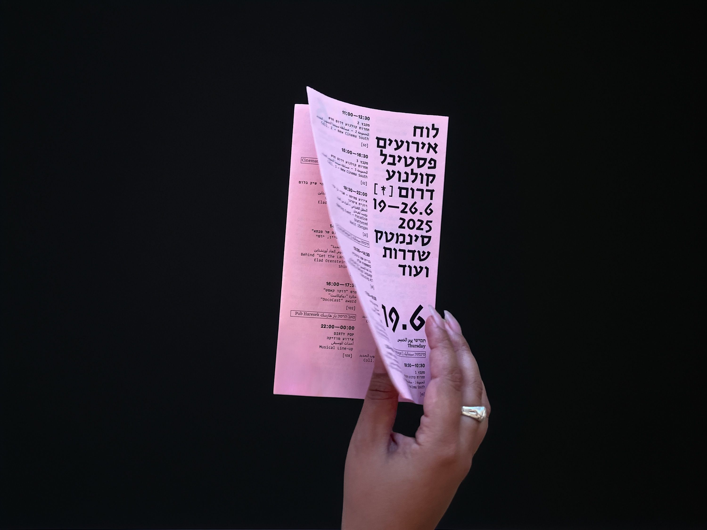 A hand holding the folded pink schedule
