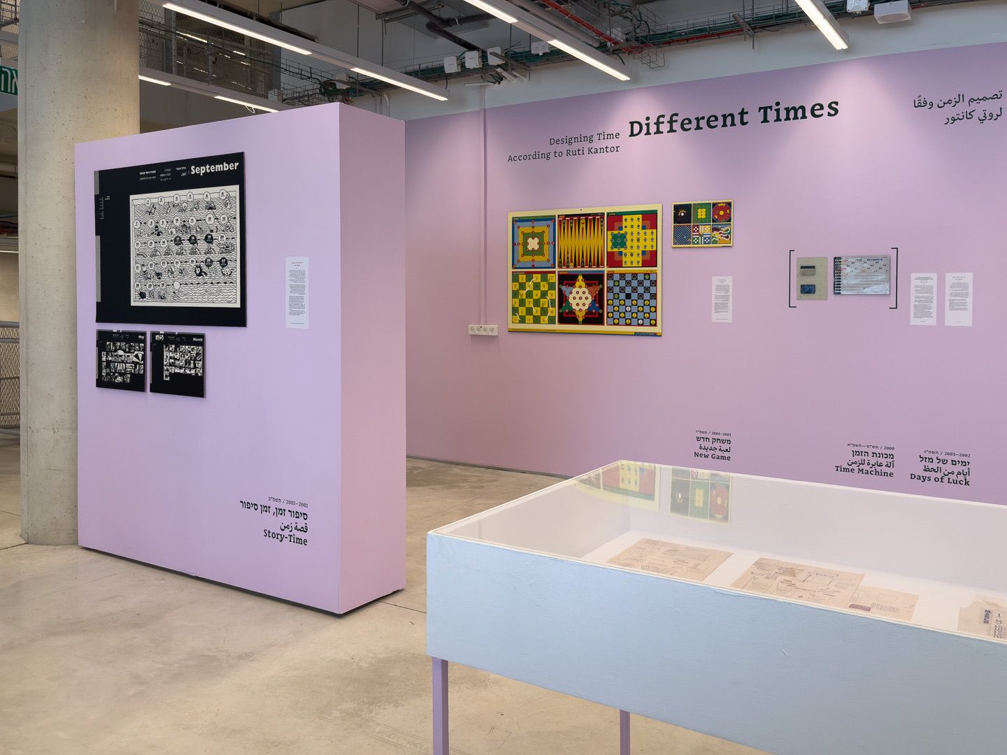 A freestanding pink wall with calendars on black, beside the title wall and a display case