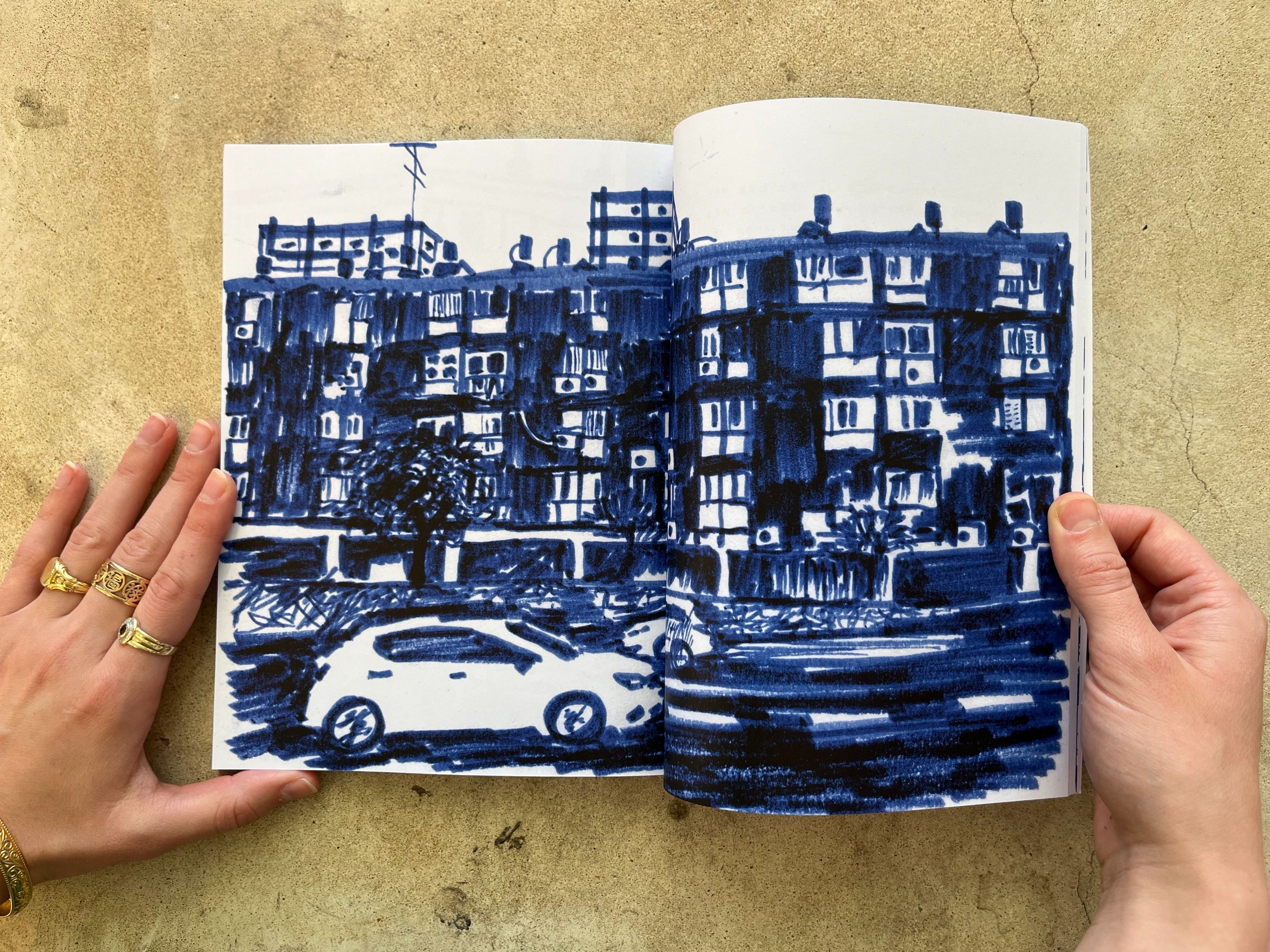 A spread drawn in blue marker: apartment buildings and a parked car